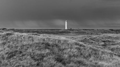 Lighthouse on field against sky