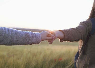 Two women holding hands at sunset in the field