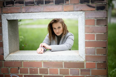 Portrait of a young woman against brick wall