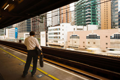 Kowloon bay, hong kong, china - man waiting for the train at station with buildings of kowloon bay 