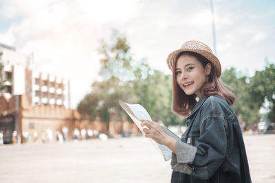 Portrait of smiling young woman standing in city