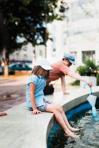 Happy european children play with water in the city fountain, child safety and freedom in the city. 