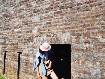 Full length of woman standing against brick wall