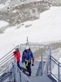 People standing by railing on snowcapped mountain