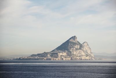 Distant view of town by sea against sky