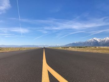 Surface level of empty road against blue sky