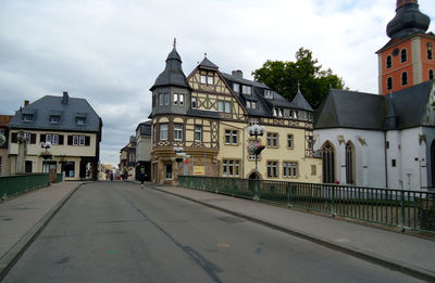 Road by buildings in city against sky