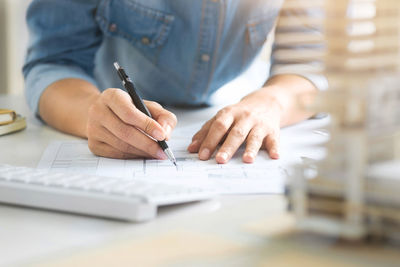 Midsection of man holding paper while sitting on table
