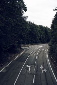 Road sign by trees against sky