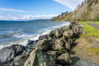 Rocks line the shore at saltwater state park in des moines, washington. it is a windy day.