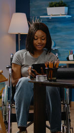 Mid adult woman using phone while sitting on table