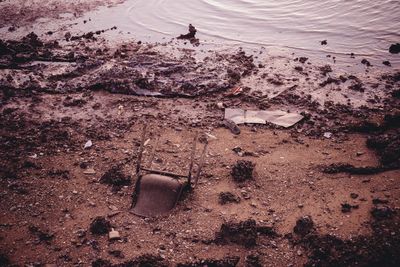 Upside down abandoned chair in sand on seashore during sunset