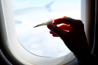 Close-up of hand holding airplane window