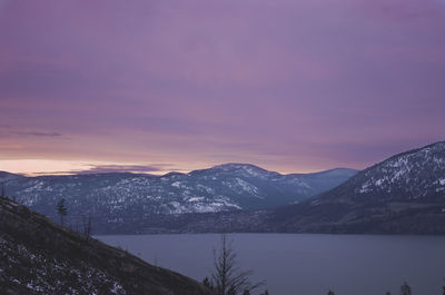 Lake amidst mountains against cloudy sky at sunset