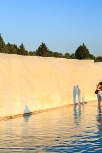 People in lake against clear blue sky