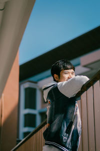 Smiling man standing by railing against building