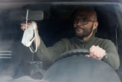 Portrait of man using mobile phone while sitting in car