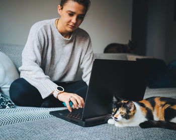 Full length of a young man using laptop at home