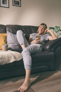 Woman using phone while sitting on sofa at home