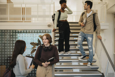 Multiracial male and female students with backpacks talking in university