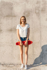 Portrait of a happy teenage girl holding a skateboard