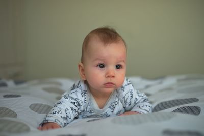 Newborn baby in pajamas relaxing in bed