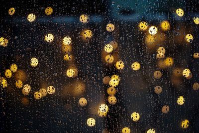 Defocused lights seen through wet glass window during monsoon