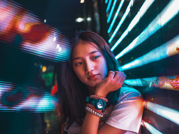 Portrait of young woman in illuminated carousel at night