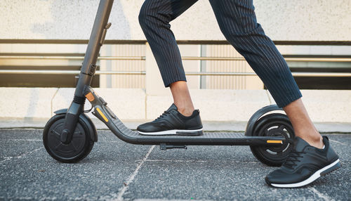 Low section of man riding push scooter on street