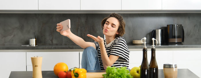 Portrait of young woman using mobile phone while sitting at home