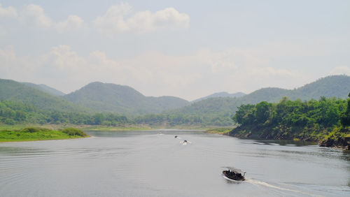 Scenic view of river by mountains against sky