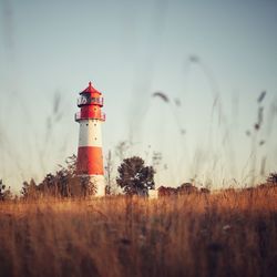 Lighthouse by sea against sky during sunset