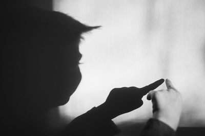 Cropped image of boy hand pointing against wall with shadow