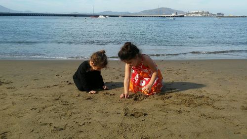 Sisters playing on sand at beach