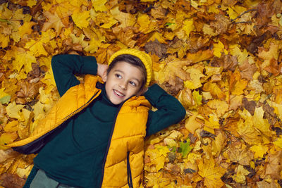 Portrait of young woman standing amidst autumn leaves