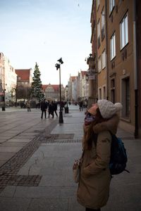 Side view of woman standing on walkway by buildings