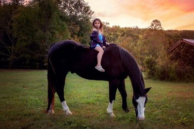 Full length of cute girl sitting on horse