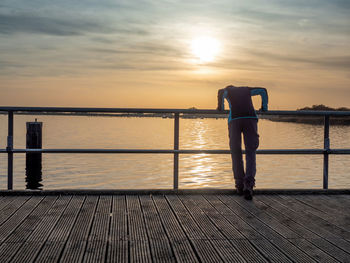 Tourist leans over railing and looks at sunset over the sea. sea pier or bridge, evening baltic sea