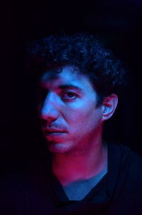 Portrait of young man against black background