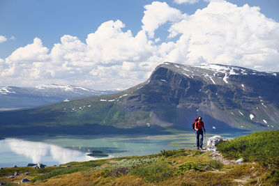 Rear view of woman looking at mountains against sky