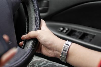 Close-up of hand holding steering wheel in car
