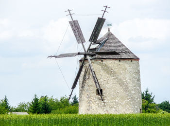 Windmill on field against cloudy sky