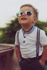 Boy wearing sunglasses while standing against sky