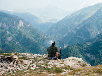 Rear view of men sitting on mountain landscape