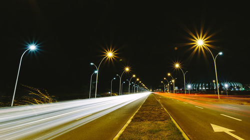 Light trails on road against sky at night