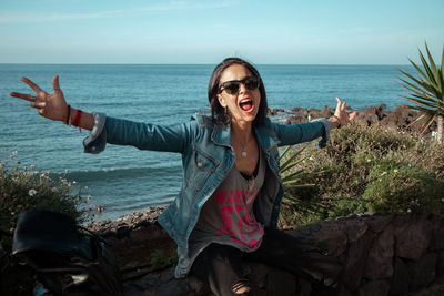 Happy young woman at beach against sky