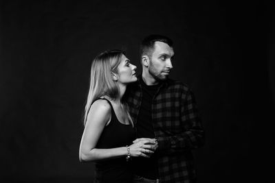 Young couple standing against black background