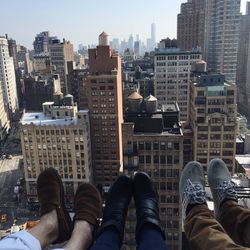 Low section of people legs by cityscape against clear sky