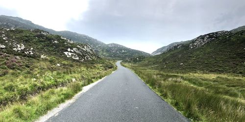 Road leading towards mountains against sky