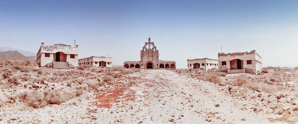 Houses on field by buildings against clear sky